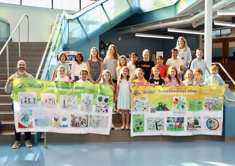 Student art contest honorees display their artwork with the theme Preserving Lewes. The contest was open to Lewes Elementary School students in grades one to five. Shown are in back (l-r) Grayson Lanan, Senumi Hawadige, Avery Andrew, Ellis Hay, Delaney Tartal, Jancely Lopez, Zoe Husbands, Angelique Cortez, Jacqueline Gonzalez Lux, Cooper Skocypec, and Principal Kim Corbidge. In front are Assistant Principal Alfredo Rodriguez, Chloe Puga-Leon, Marcayla Bullock, Liliana Kroc, Charlotte Roach, Sophia Bueno, Olivia Dickinson, Lily Armstrong-Watts, Brooke DeStefano, Duke Owen and Peter Hastings.